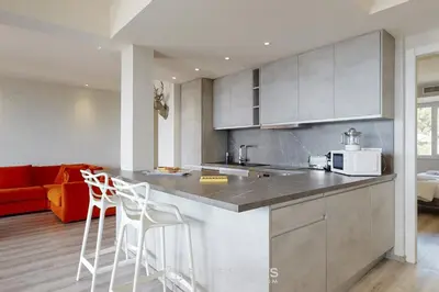 a kitchen with a counter and two white stools at Suite Horizon FSHH in Beaulieu-sur-Mer