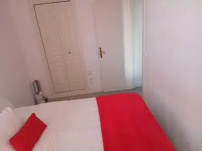 a bedroom with a white bed with a red pillow at Bel appartement pour vos séjours sur la côte in Nice