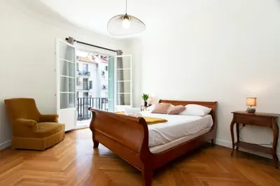 a bedroom with a bed and a chair and a window at Maison Bianchi - Victor Hugo in Nice