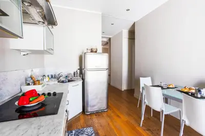 a kitchen with a refrigerator and a table with chairs at LUNG ARNO AP4300 By Riviera Holiday Homes in Nice