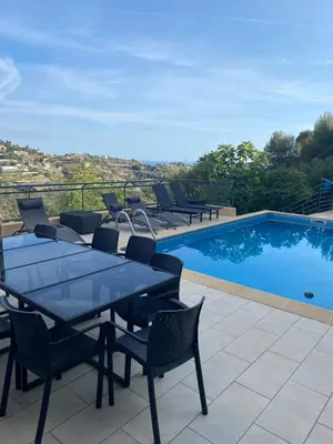 a patio with a table and chairs next to a swimming pool at Spacieuse Villa Niçoise au calme avec piscine in Nice