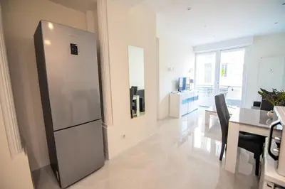 a kitchen with a stainless steel refrigerator and a dining room at Новая 3-комнатная квартира на 2й линии от моря. in Nice