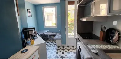 a small kitchen with blue walls and a table at SoNiceRiviera in Nice