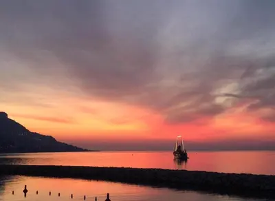a boat sitting on the water at sunset at Stunning Beaulieu Sur mer Retreat Chic with Air-Conditioning and Breathtaking Views in Beaulieu-sur-Mer
