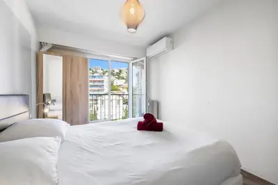 a red teddy bear sitting on top of a white bed at Le Hammam Azur in Nice