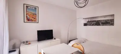a white living room with a tv and a couch at Nice Studio With View Near Beach in Nice