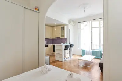 a room with a bed and a living room with a kitchen at Appartement Lamartinesque - Welkeys in Nice