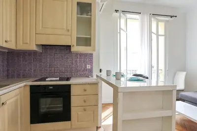 a kitchen with wooden cabinets and a counter top at Appartement Lamartinesque - Welkeys in Nice