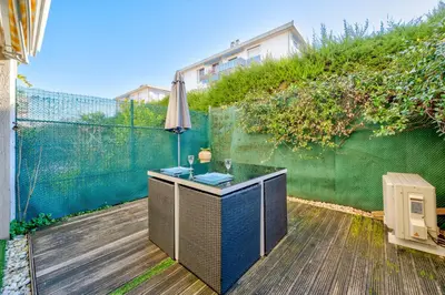 a patio with a table with an umbrella and a fence at Charmant studio in Cagnes-sur-Mer