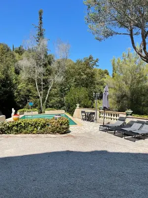a swimming pool with two lounge chairs and an umbrella at Studio en bas de villa avec piscine proche bord de mer in Cagnes-sur-Mer