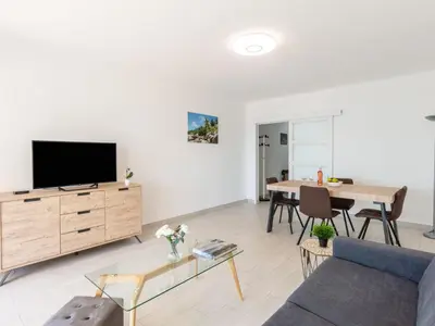 a living room with a tv and a table at Apartment Les Trois Caps by Interhome in Cagnes-sur-Mer