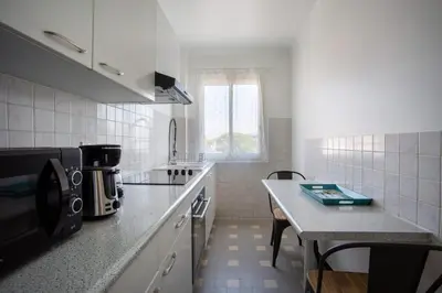 a white kitchen with a counter and a table at Apartment T2 air-conditioned sea view in Saint-Laurent-du-Var