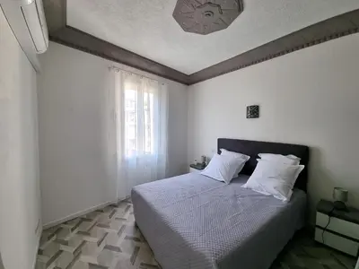 a bedroom with a bed with white sheets and a window at Bel appartement 2 chambres climatisé centre ville in Nice