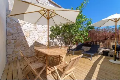 a wooden table and chairs with an umbrella on a deck at Magnifique pavillon indépendant T2 Nice in Nice