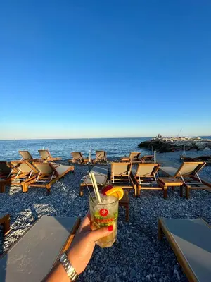 a person holding a drink in front of the beach at cagnes promenade in Cagnes-sur-Mer