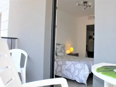 a room with a bed and a table and a mirror at Appartement Neuf 3 Pièces avec Terrasse et Garage, Cagnes-sur-Mer - FR-1-252A-88 in Cagnes-sur-Mer