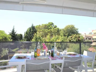 a table with chairs and bottles and drinks on a balcony at Appartement Neuf 3 Pièces avec Terrasse et Garage, Cagnes-sur-Mer - FR-1-252A-88 in Cagnes-sur-Mer