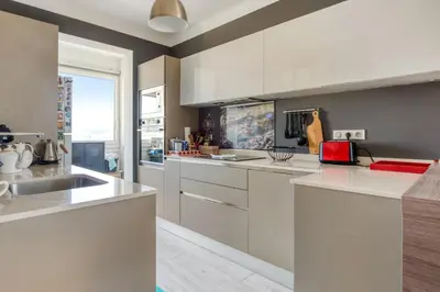 a kitchen with white counters and a large window at Appartement Ayres - Welkeys in Nice