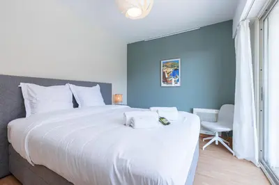a bedroom with a large white bed and a chair at Amazing Sea View 2Bdr Swimming Pool Parking in Villefranche-sur-Mer