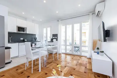 a white kitchen with a dining table and chairs at Quiet 1 Bdr Downtown Terrace AC & Parking in Nice