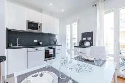 a kitchen with white cabinets and a glass table at Quiet 1 Bdr Downtown Terrace AC & Parking in Nice