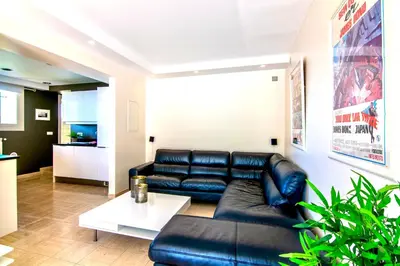 a living room with a black leather couch and a table at Villa Soleil d'Or in Villefranche-sur-Mer