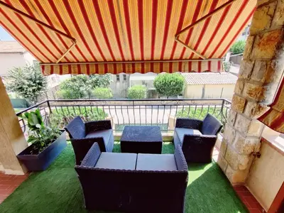 a patio with chairs and a table and an umbrella at La Villa Castel - Haut de villa - parkings- 3 chambres - 8 couchages - jardin - barbecue in Cagnes-sur-Mer