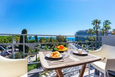 a table with food on a balcony with a view of the ocean at PALAIS ALBERT 1ER AP4292 By Riviera Holiday Homes in Nice
