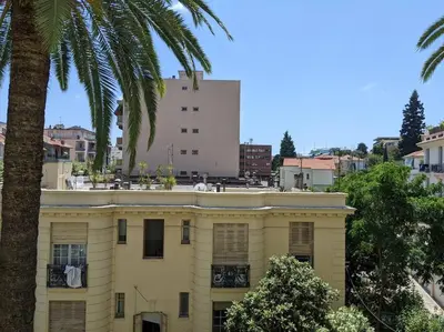 a yellow building with a palm tree in front of it at Amazing 2-bedroom apartment in Nice near the beach in Nice