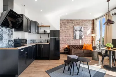 a kitchen with black cabinets and a living room at Nice Renting - CAMBRAI - Luxurious Sea View Terrasse - King Bed - Parking - AC - fully equipped in Nice