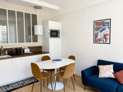 a kitchen and living room with a table and a blue couch at Mediterranee - un trois pièces à deux pas de la plage in Nice
