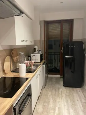 a kitchen with a black refrigerator and white cabinets at I Love you Berry Berry Much! in Nice
