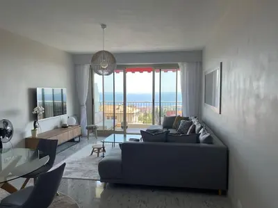 a living room with a couch and a table at Exceptional sea view, tennis, parking, WiFi in Nice