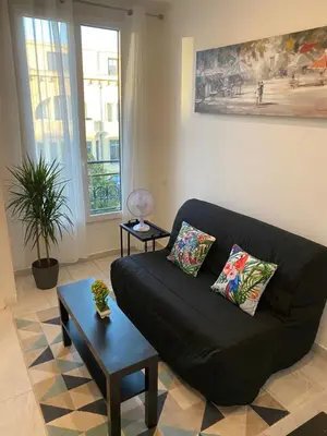 a living room with a black couch and a table at Studio sur avenue jean médecin à Nice in Nice