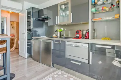 a kitchen with gray cabinets and stainless steel appliances at Appartement Rivage - Welkeys in Cagnes-sur-Mer