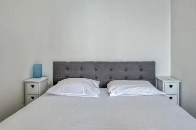 a white bed with two nightstands and a blue vase at Appartement Rivage - Welkeys in Cagnes-sur-Mer