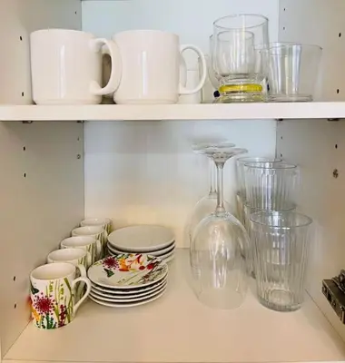 a shelf with plates and cups and a wine glass at Studio récemment rénové proche gare et ville in Nice