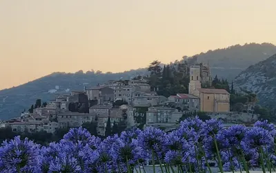 a town on top of a hill with purple flowers at Appartement de luxe Eze village vue mer avec piscine in Èze