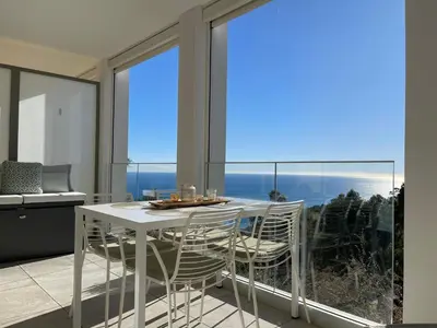 a white table and chairs in a room with a large window at Appartement de luxe Eze village vue mer avec piscine in Èze