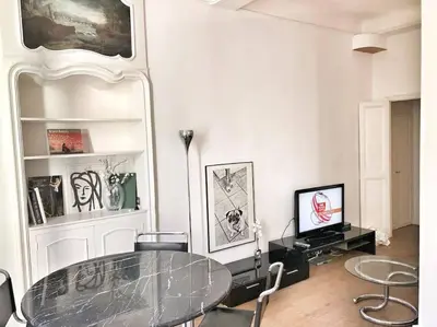 a dining room with a glass table and a television at Homelivia, VIEUX NICE, appartement de charme, clim balcon in Nice