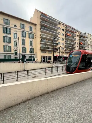 a red train on a road with buildings in the background at Studio central avec balcon- Plage - Tram - Aéroport in Nice