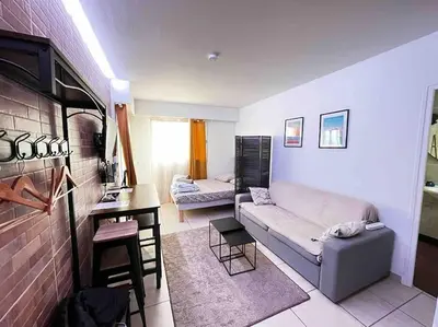 a living room with a couch and a table at Parking + piscine, tout confort, proche aéroport & mer in Saint-Laurent-du-Var