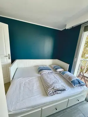 a bed in a room with a blue wall at Appartement bord de mer avec piscine in Saint-Laurent-du-Var
