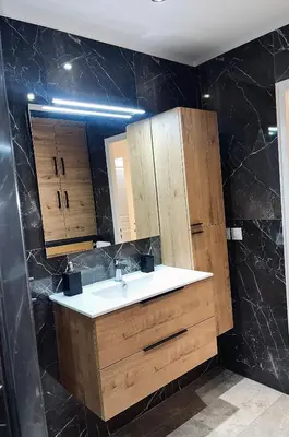 a bathroom with a sink and wooden cabinets at Appartement bord de mer avec piscine in Saint-Laurent-du-Var