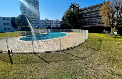a fence around a swimming pool with a fountain at Appartement bord de mer avec piscine in Saint-Laurent-du-Var