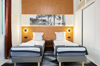 a hotel room with two beds and a desk at La plume de Paul in Nice