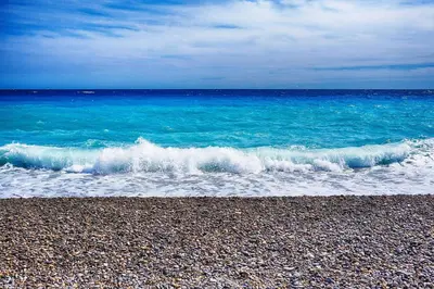 a wave breaking on a beach near the ocean at Ferienwohnung Les Oliviers über den Dächern von Nizza ruhig sonnig Meerblick Pool Tiefgarage Parkplatz in Nice