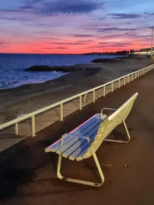a bench sitting on the beach near a fence at Bonaparte - Nice in Nice
