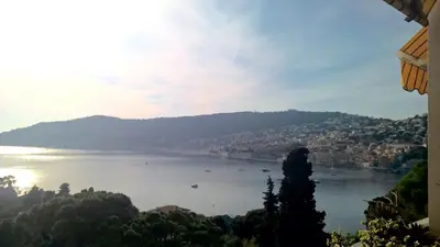a view of a large body of water with trees at Vintage flat on Villefranche bay - free car park in Villefranche-sur-Mer