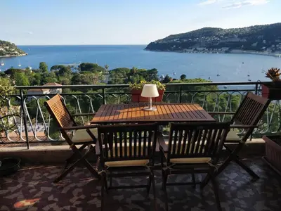 a table and chairs on a balcony with a view of the ocean at Vintage flat on Villefranche bay - free car park in Villefranche-sur-Mer